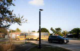 Solar-powered streetlight near a school area in Florida with a school bus in the background.