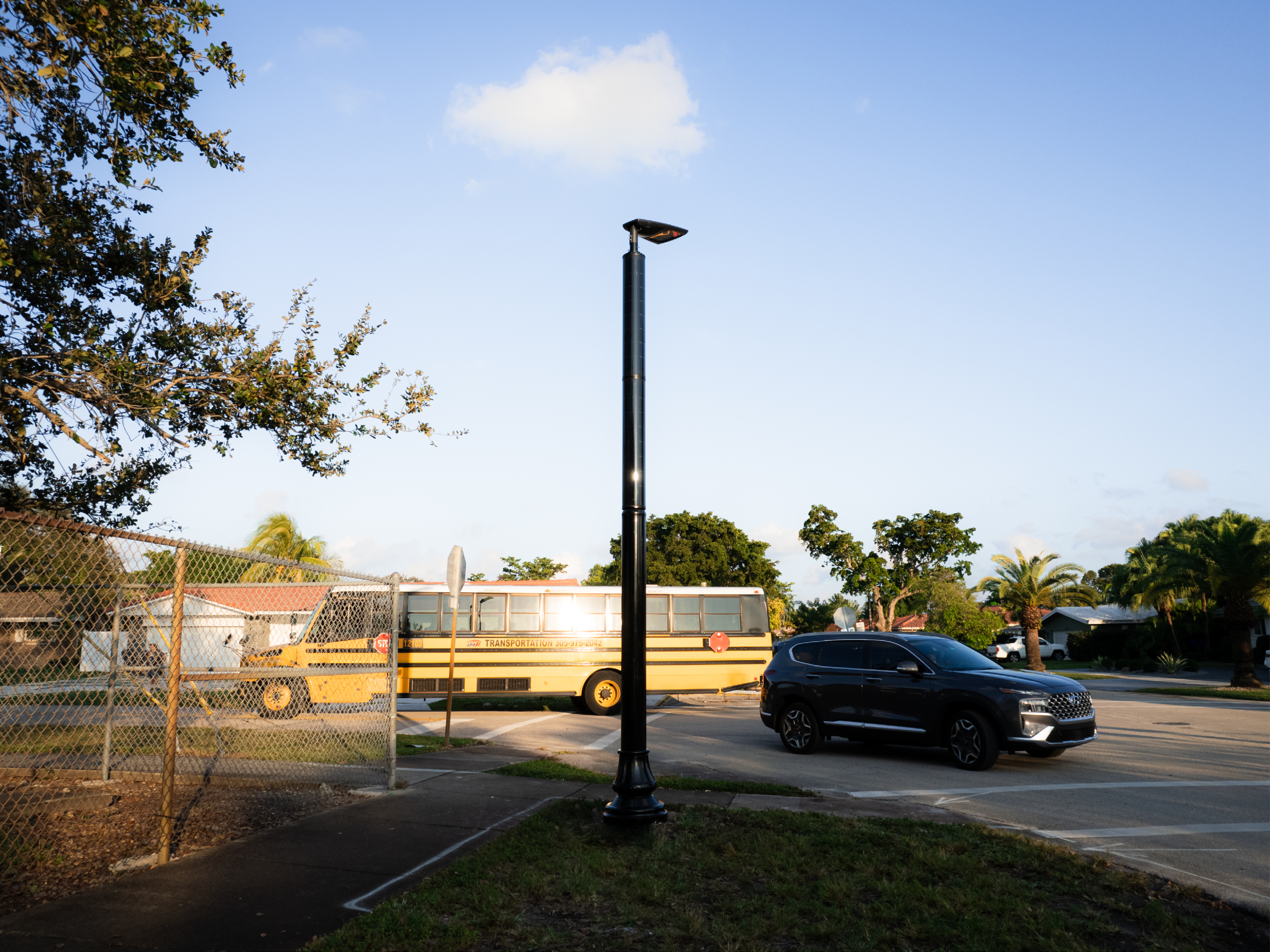 Solar-powered streetlight near a school area in Florida with a school bus in the background.