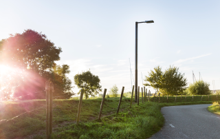 Solar streetlight near a rural road and open landscape in Numansdorp at sunset.