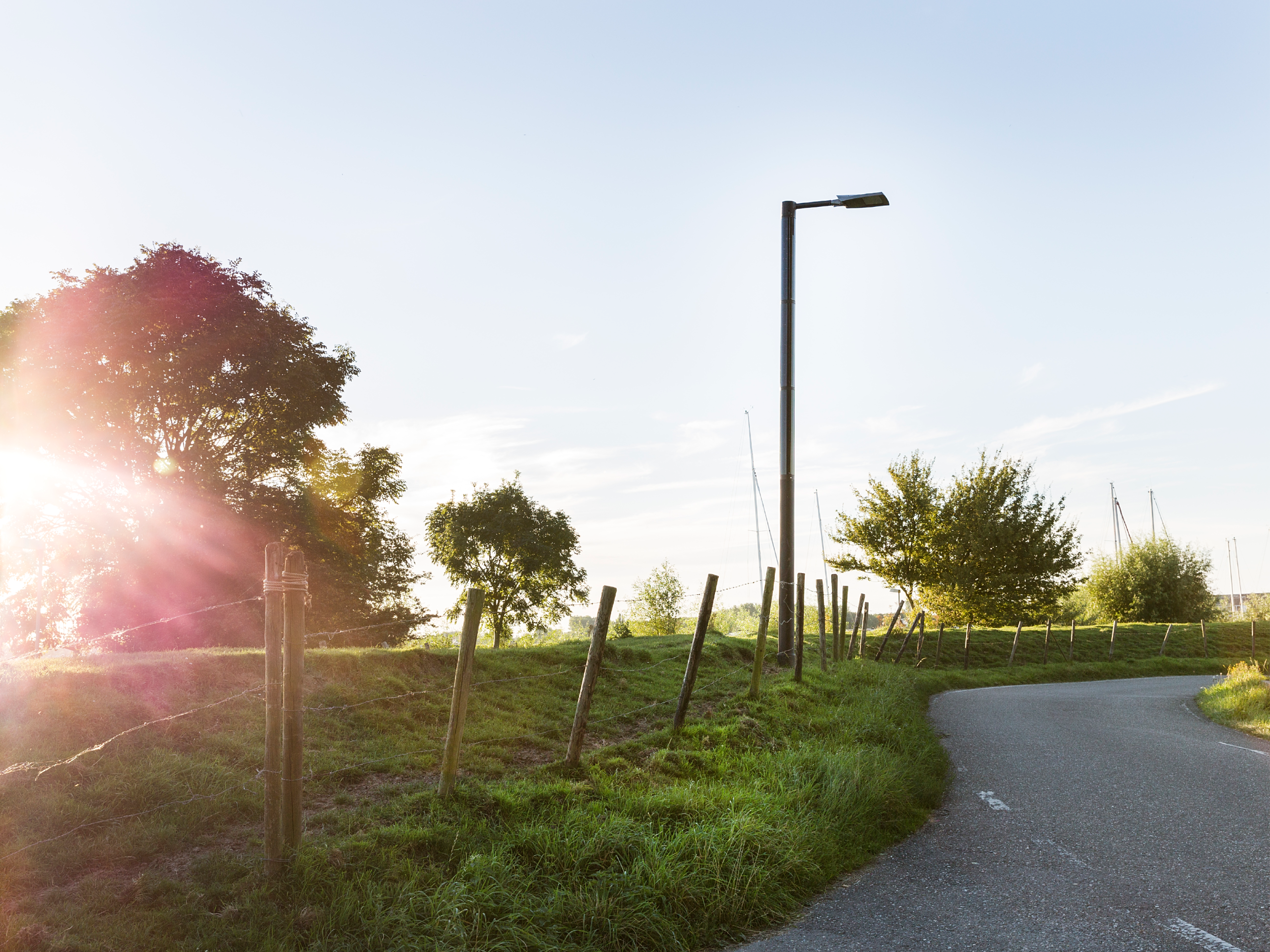 Solar streetlight near a rural road and open landscape in Numansdorp at sunset.